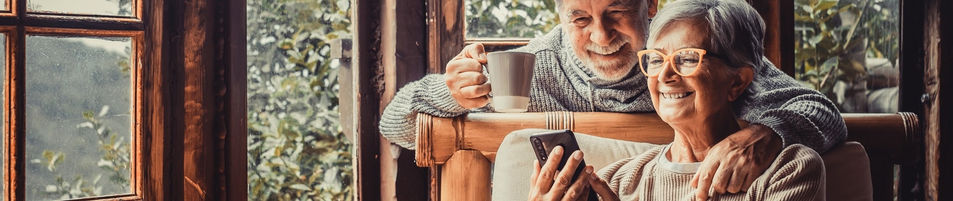 Een paar twee oude en volwassen mensen die thuis samen de telefoon gebruiken op de bank.